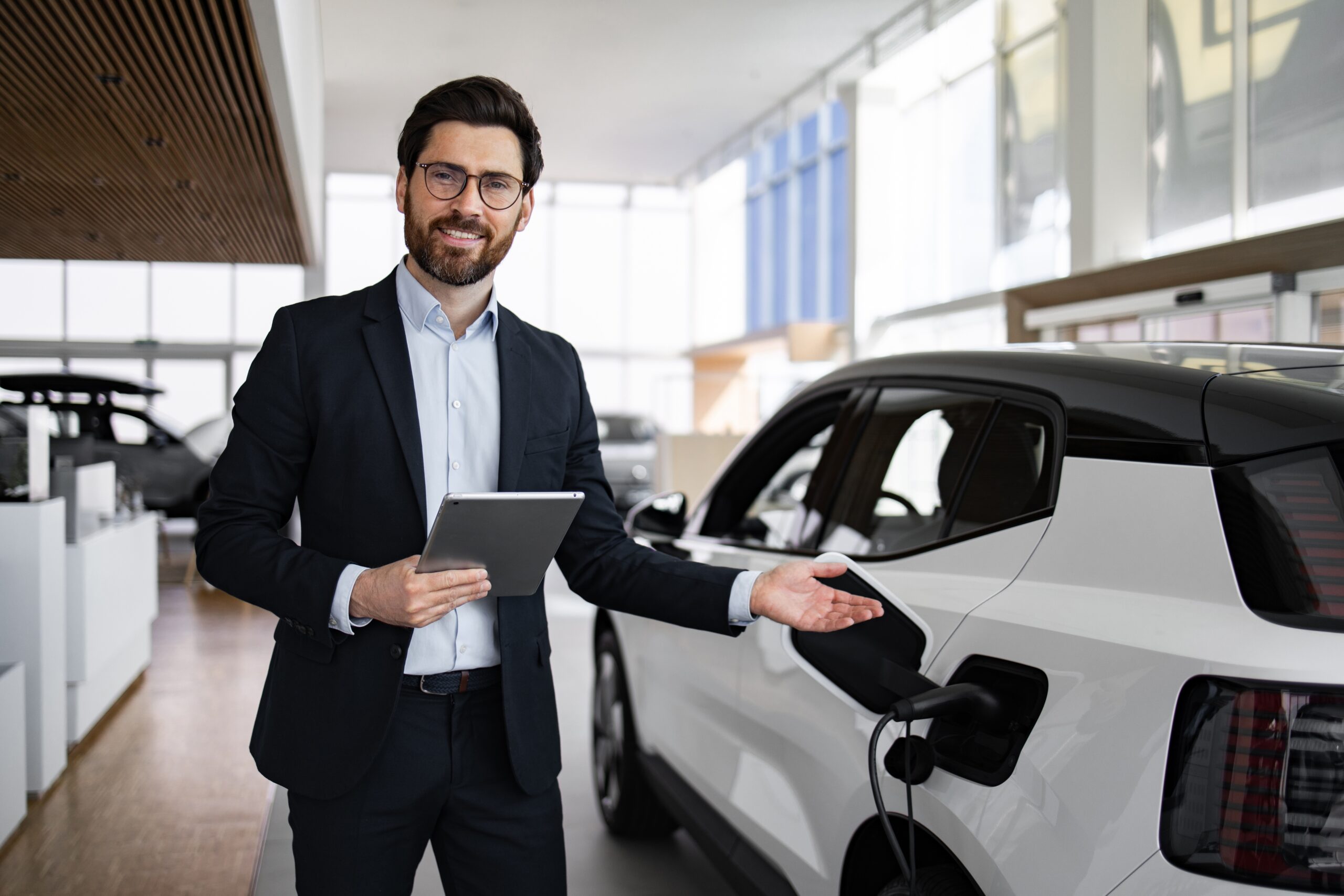 Smiling,Dealer,Showcasing,Electric,Car,In,Modern,Vehicle,Dealership.,Professional