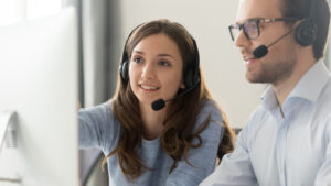 man and woman with headsets looking at monitor