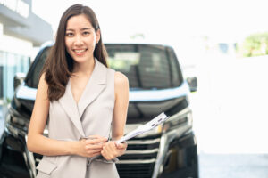 asian woman holding a clipboard in front of SUV